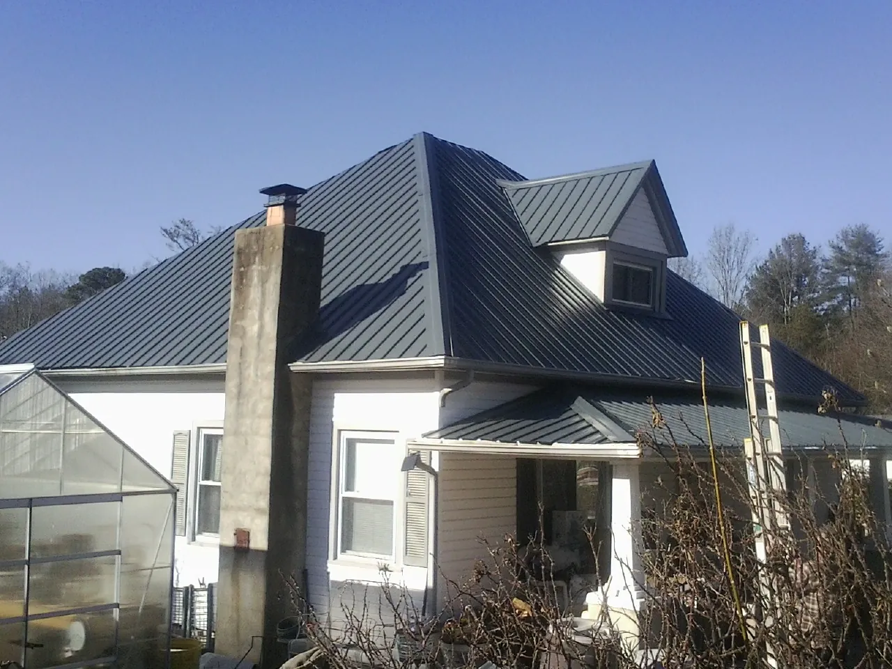 Dark blue standing seam metal roof on a white farmhouse with dormer — Slate & Tile Roof Repair by Roofing Brothers in Lake Hiawatha