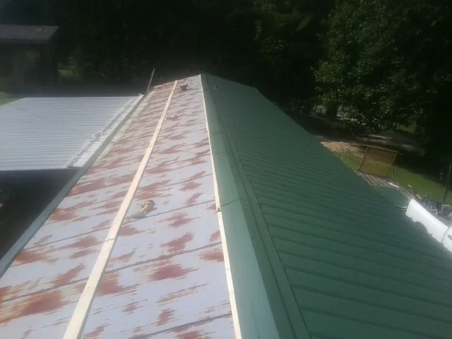 Old rusted panels beside newly installed green metal roofing — Wind Damage Roof Repair by Roofing Brothers in Lake Hiawatha
