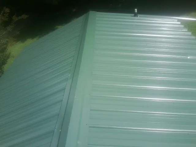 New green metal panels meeting at the ridge of a roof — Flat Roof Repair work by our crew in Lake Hiawatha