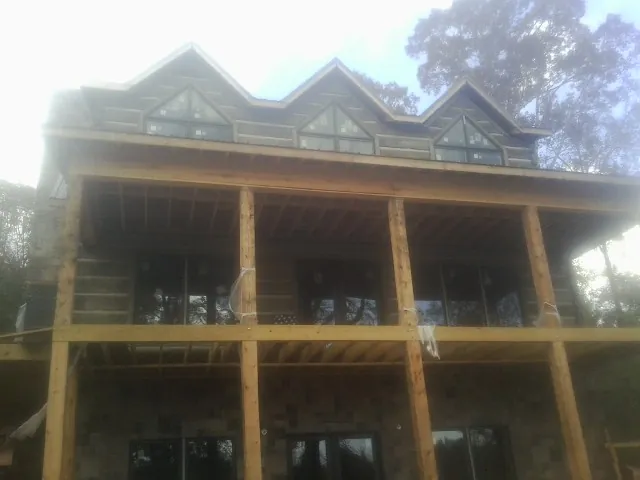 Dormers and porch framing on a large log home under construction — Roof Coating work by our crew in Lake Hiawatha