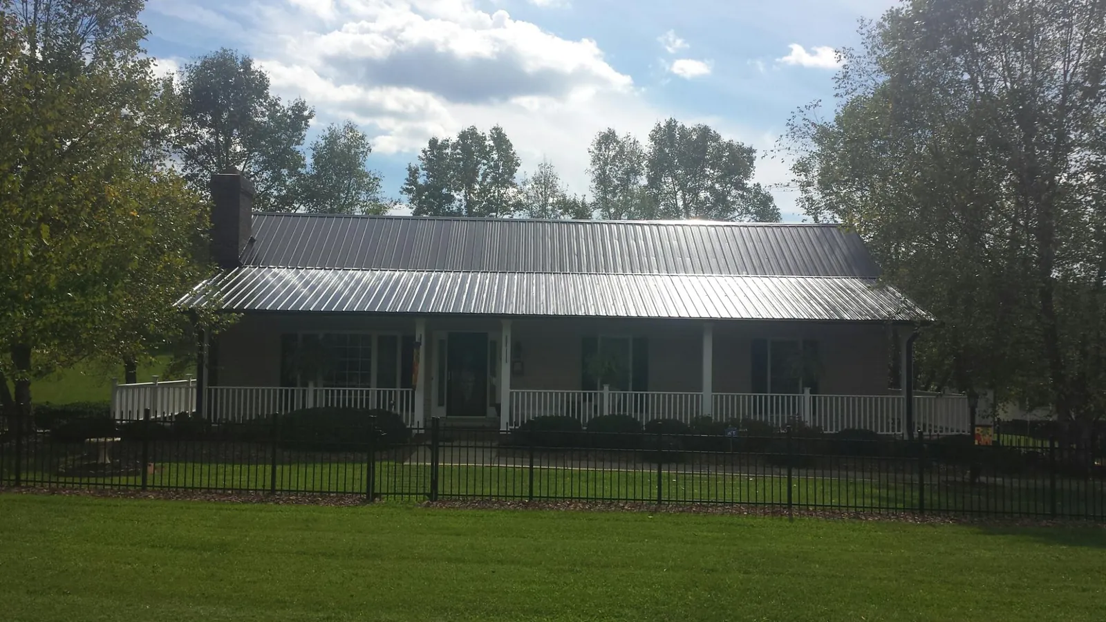 Gray metal roof on a brick ranch with a full width front porch — Gutter Guard Installation work by our crew in Lake Hiawatha