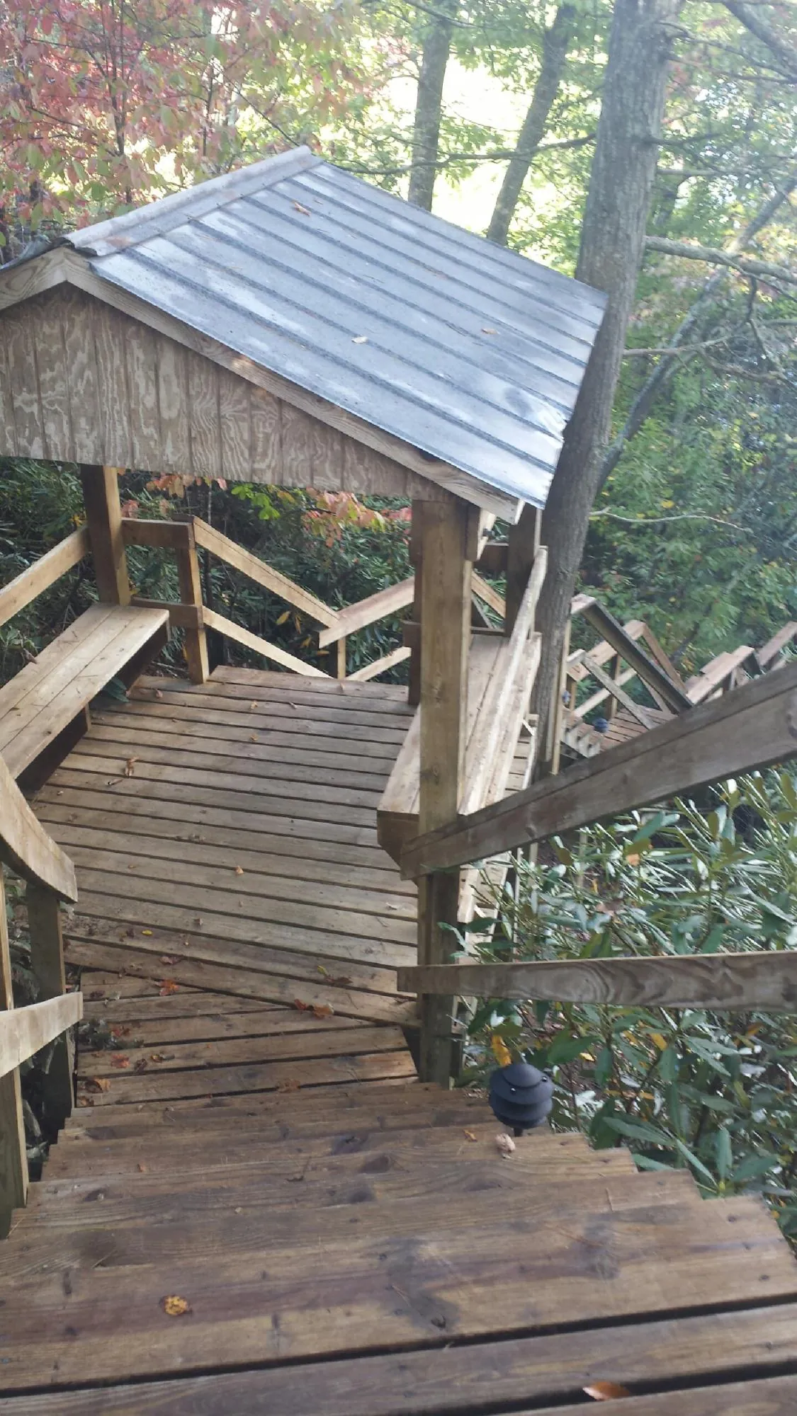 Metal roofed shelter over wooden steps on a wooded walkway — Skylight Repair & Installation work by our crew in Lake Hiawatha