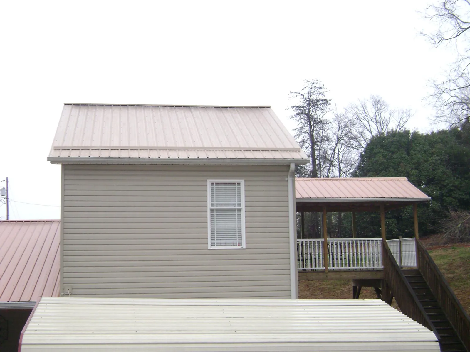 Tan metal roofs on a two story addition and attached porch, from a Roof Replacement job in Lake Hiawatha