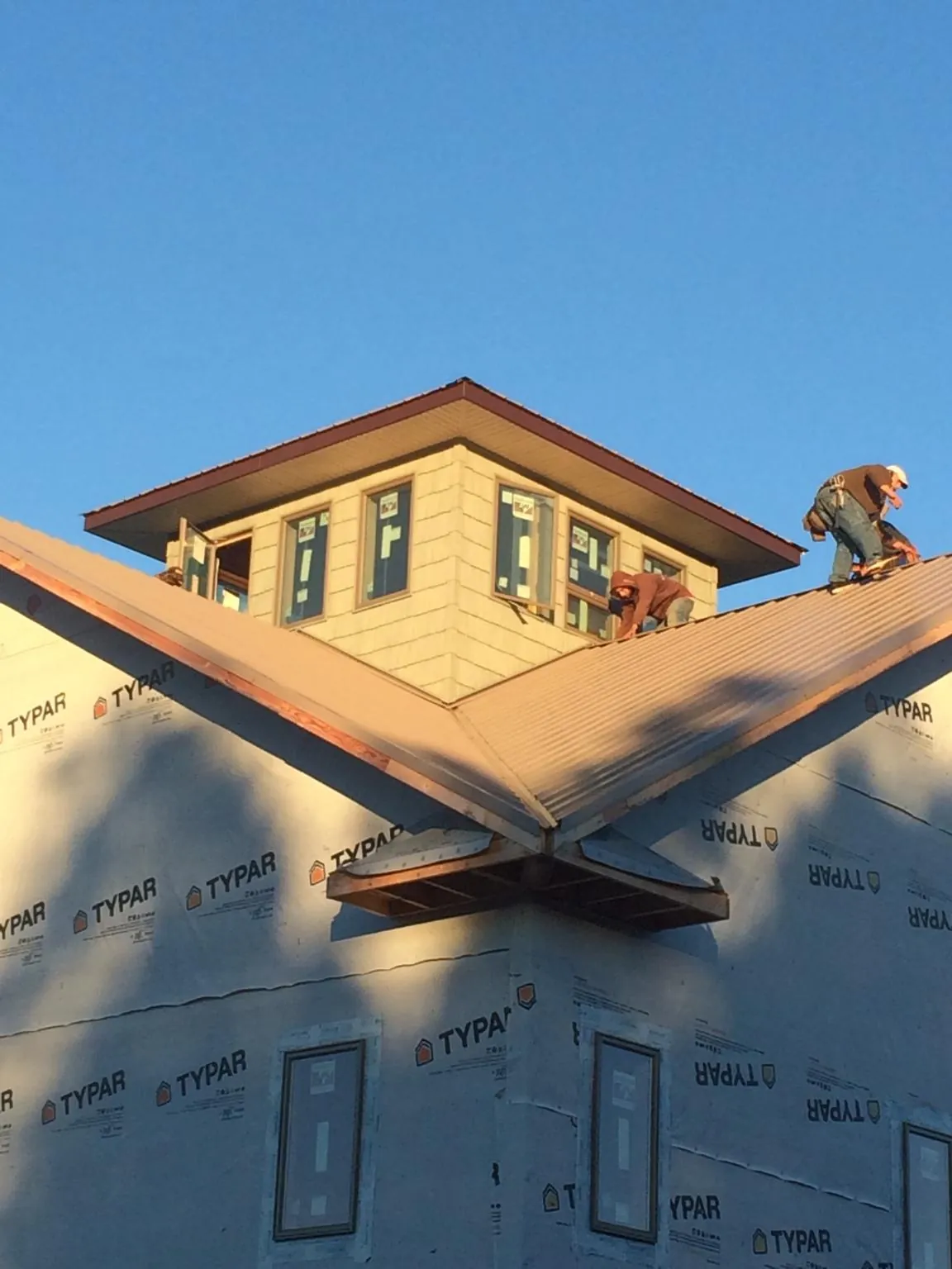 Roofers working around a rooftop cupola on a new metal roof at sunset — Roof Waterproofing in Lake Hiawatha by Roofing Brothers